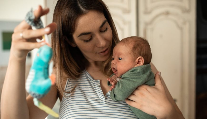 Kobieta trzyma niemowlaka na rękach z zabawką