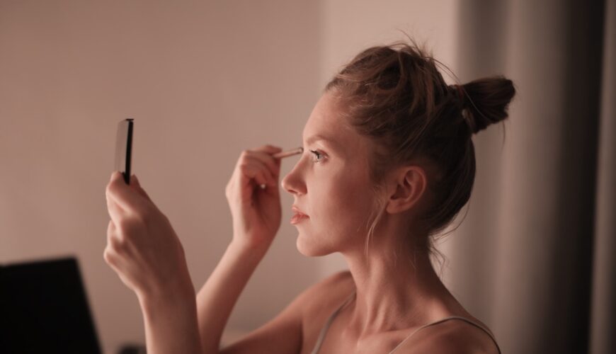 Kobieta przed lustrem robi sobie modny makijaż