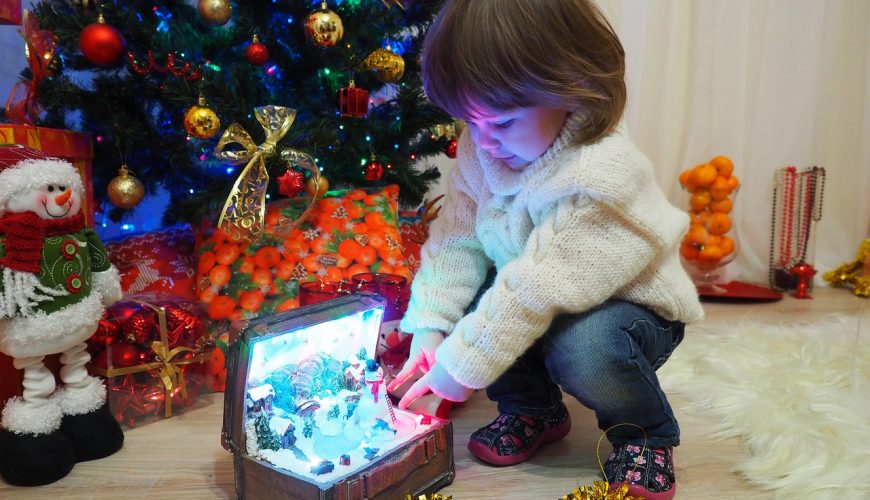 Dziewczynka wyciąga z pudełka świąteczne figurki na święta